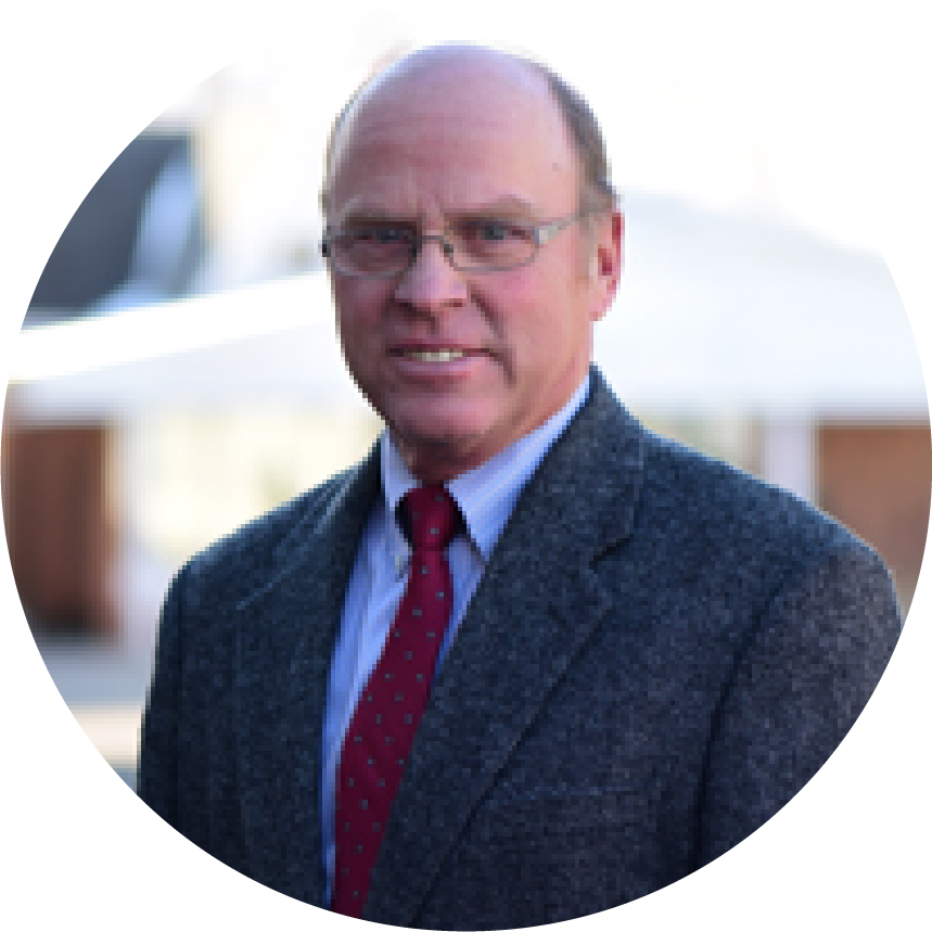 Headshot circle edit photo of Nels Nyblad in gray suit with red tie