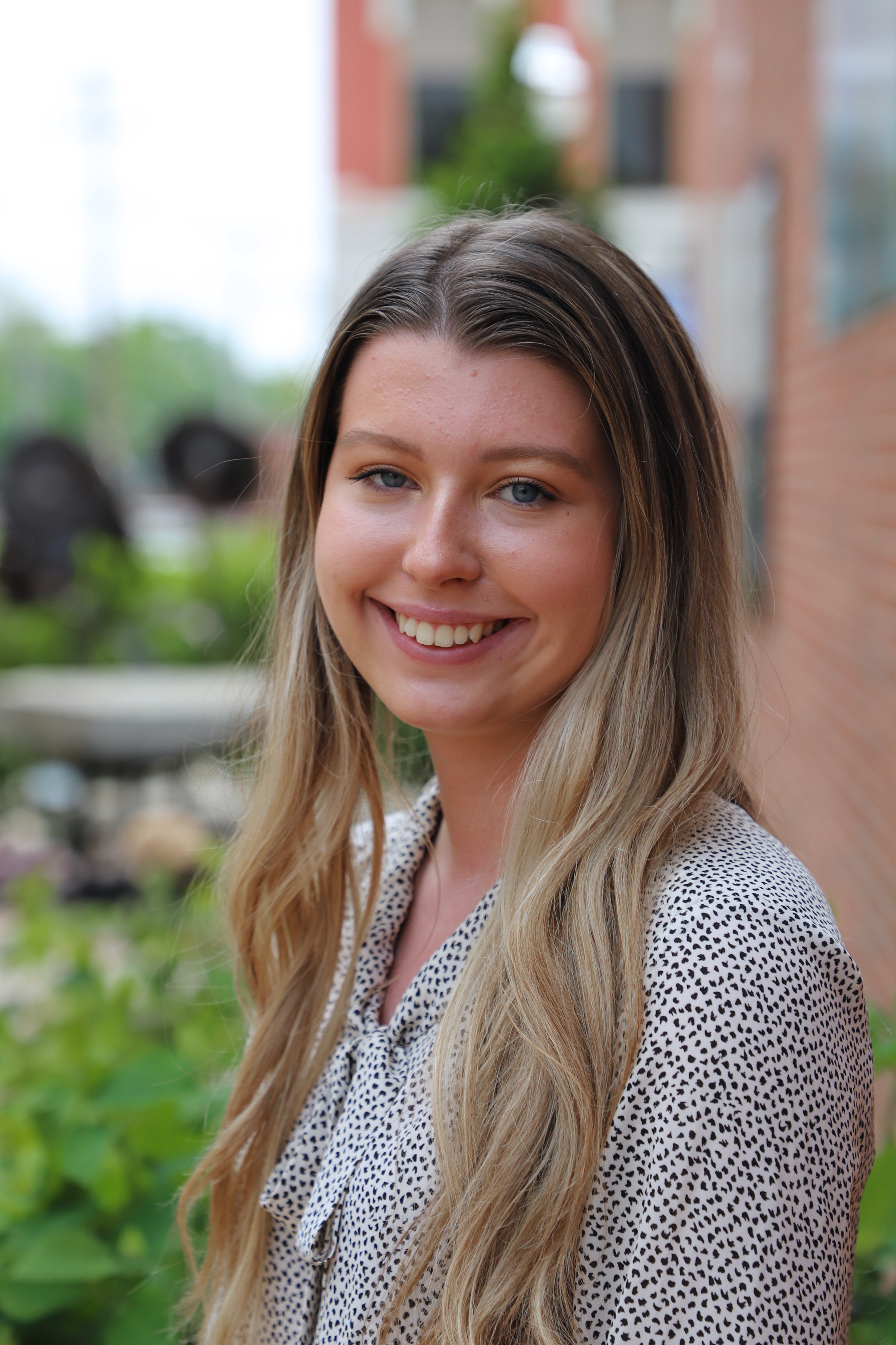 Headshot of Olivia Phillips with garden and brick wall in background